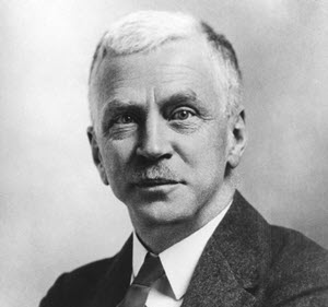 Portrait en noir et blanc d'un homme d'âge moyen en complet-cravate regardant droit devant d'un air sérieux.