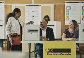 Des  préposés au scrutin servent un électeur
