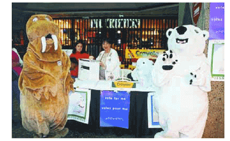 This photo shows mascots serving as candidates, and Elections Canada’s Community Relations Officer Denise McCulloch during an election simulation for families who visited a Montréal shopping centre last Easter.