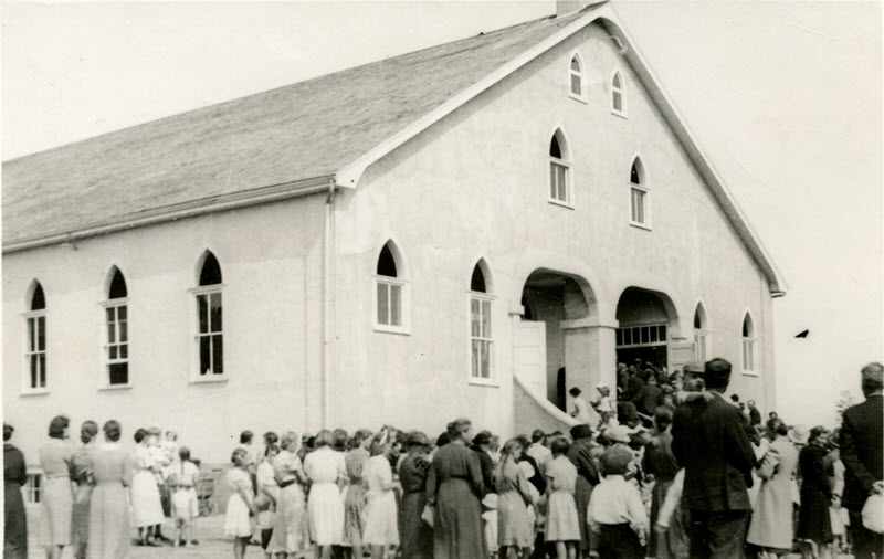 Black-and-white photo of a crowd of people gathering before a large church.